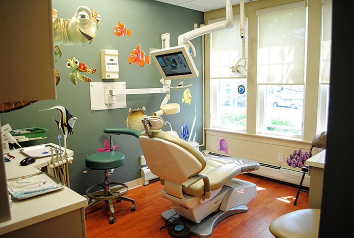 An exam room with a dental chair in the center facing a bank of windows