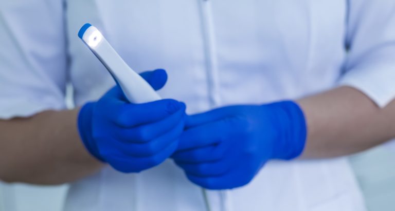 A dental assistant holding an intraoral camera